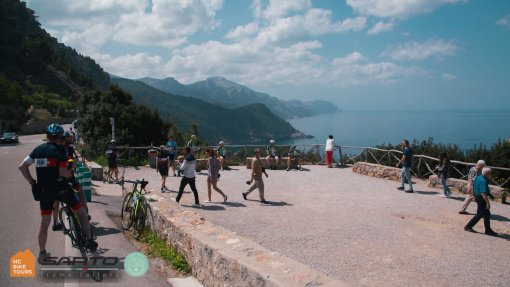 Cyclists and tourists at viewing spot on the coast of Mediterranean in Mallorca, Spain