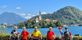 Group of cyclists posing for a picture with lake Bled in the background in Slovenia