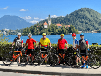 Group of cyclists posing for a picture with lake Bled in the background in Slovenia