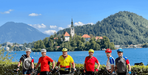 Group of cyclists posing for a picture with lake Bled in the background in Slovenia