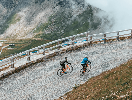 Cyclists riding up Gross Glockner cobbled mountain pass in Austria