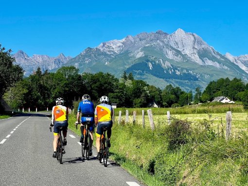 Cyclists riding towards mountains during French Pyrenees bike trip in July 2023