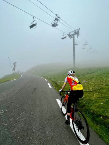 Cyclist riding towards Col du Tourmalet in the mist during French Pyrenees bike trip in July 2023