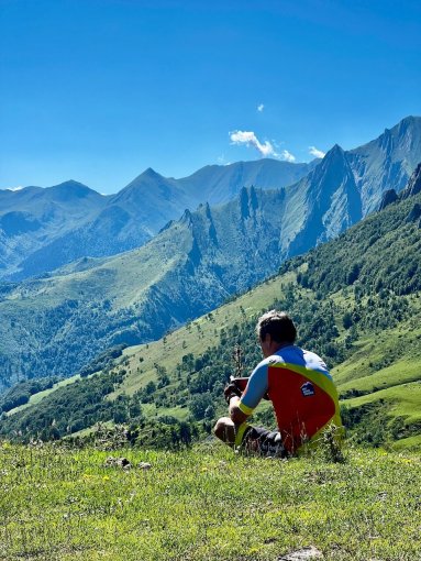 HC Bike Tours guest enjoying a rest brake sitting in the meadow during French Pyrenees bike trip in July 2023