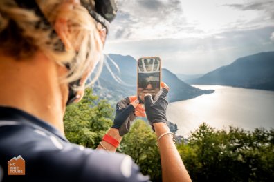 Cyclist taking a photograph with Lake Como during a bike trip in Italy