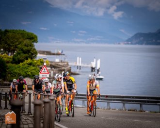 Cyclists riding in a group with Lake Como in the background in Italy