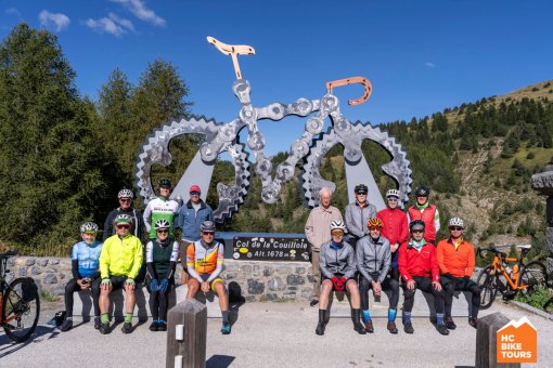 Team photo in front of the sign and large metal bike monument at Col de la Couillole.