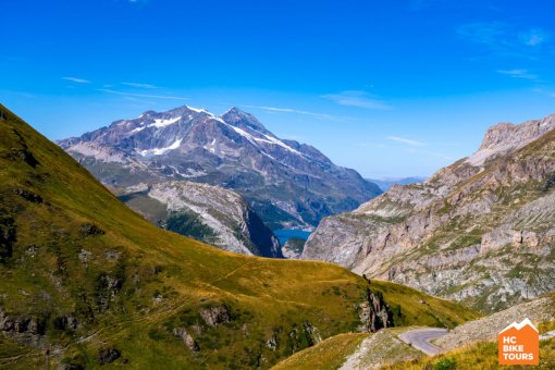 Cycling path winding through mountains, passing by serene lakes.